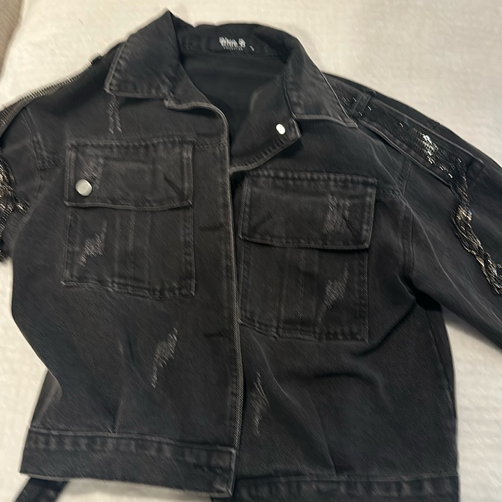 Black denim jacket with embellished shoulders.